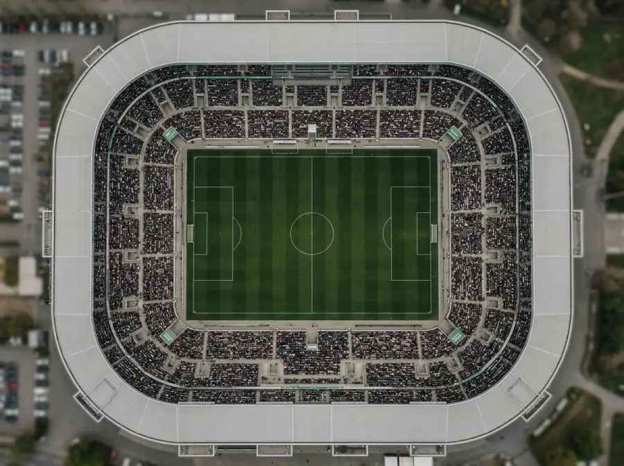 Luftaufnahme eines modernen Fußballstadions mit gefüllten Rängen als Symbolbild für die 16 Spielorte der WM 2026